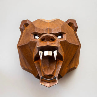 Sculpture murale d'une tête d'ours en métal avec ses deux bras qui sortent du mur fabriquée par l'artiste Cyril Maire, cette sculpture est fabriquée en acier corten et les yeux, les dents et les griffes de l'ours sont en inox brillant