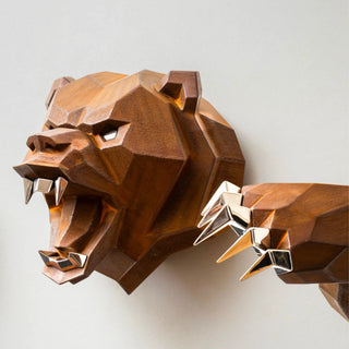 Sculpture murale d'une tête d'ours en métal avec ses deux bras qui sortent du mur fabriquée par l'artiste Cyril Maire, cette sculpture est fabriquée en acier corten et les yeux, les dents et les griffes de l'ours sont en inox brillant