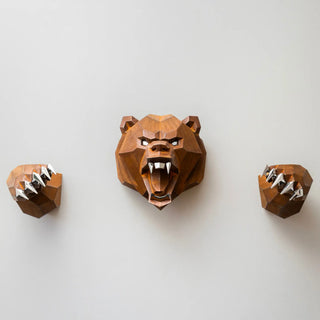 Sculpture murale d'une tête d'ours en métal avec ses deux bras qui sortent du mur fabriquée par l'artiste Cyril Maire, cette sculpture est fabriquée en acier corten et les yeux, les dents et les griffes de l'ours sont en inox brillant