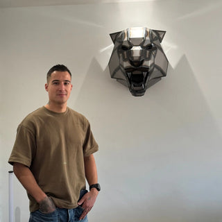 Cyril Maire, artiste, sculpteur d'art métalliques avec sa sculpture tête de tigre accrochée sur un mur